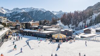 Belebtes Skiresort mit Azurblauem Himmel und schneebedeckten Bergen.