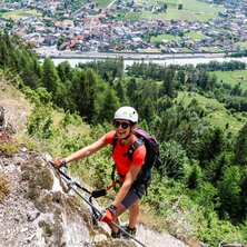 A person climbs a rock face with equipment.