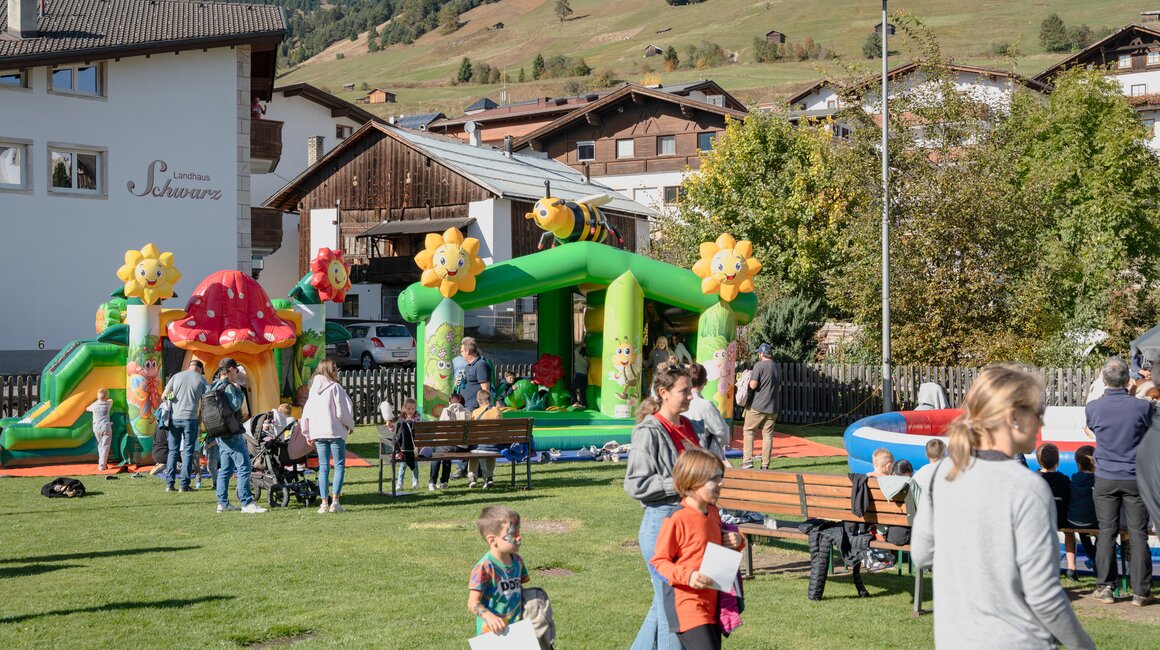 Children enjoying a festival with bouncy castles in a picturesque setting.