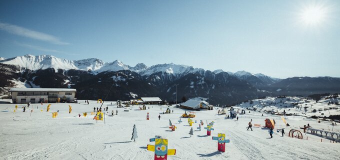 Winter landscape with skiers and colorful figures in the snow.