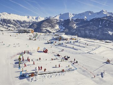 Large snowy area with skiers and ski schools in winter.