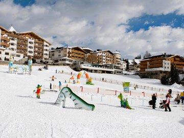 Snow-covered area with children’s ski facilities and hotels.