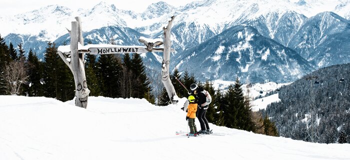 Twee skiërs in de Alpen onder een bord in de sneeuw.