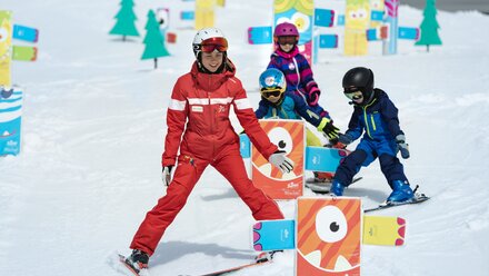 Children learning to ski with guidance in a vibrant setting.