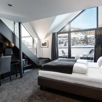 Elegantes Zimmer mit Doppelbett und freiem Blick auf die Berge.