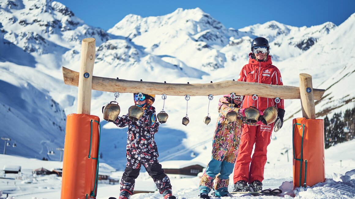 Three people at a ski station in the mountains.