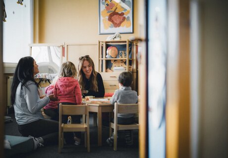 Eine Frau und Kinder spielen in einem Klassenzimmer.