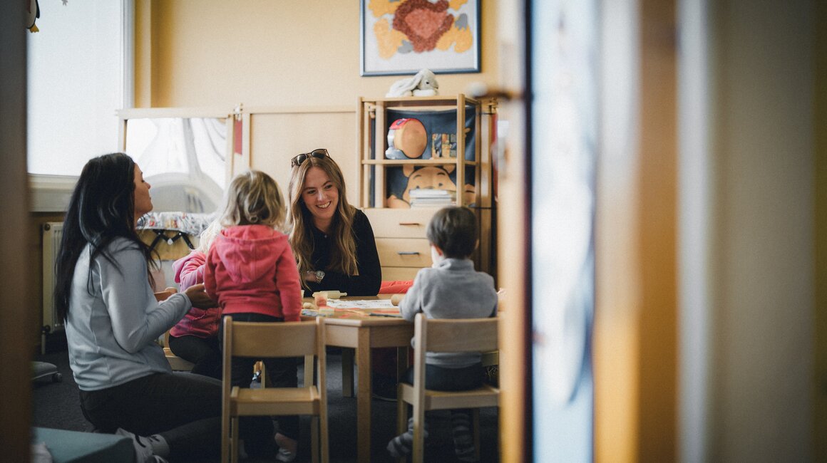 Eine Frau und Kinder spielen in einem Klassenzimmer.