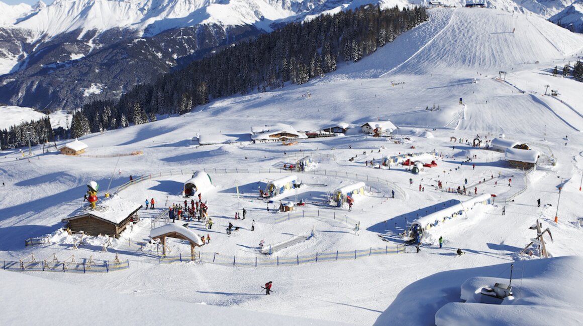 Schneebedeckte Berge mit Ski-Resort und vielen Skifahrern.