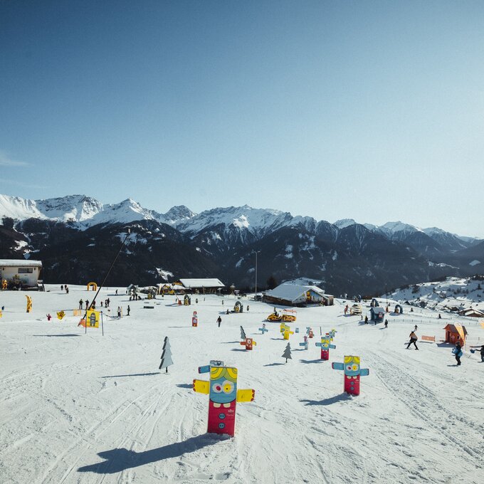 Winter landscape with skiers and colorful figures in the snow.