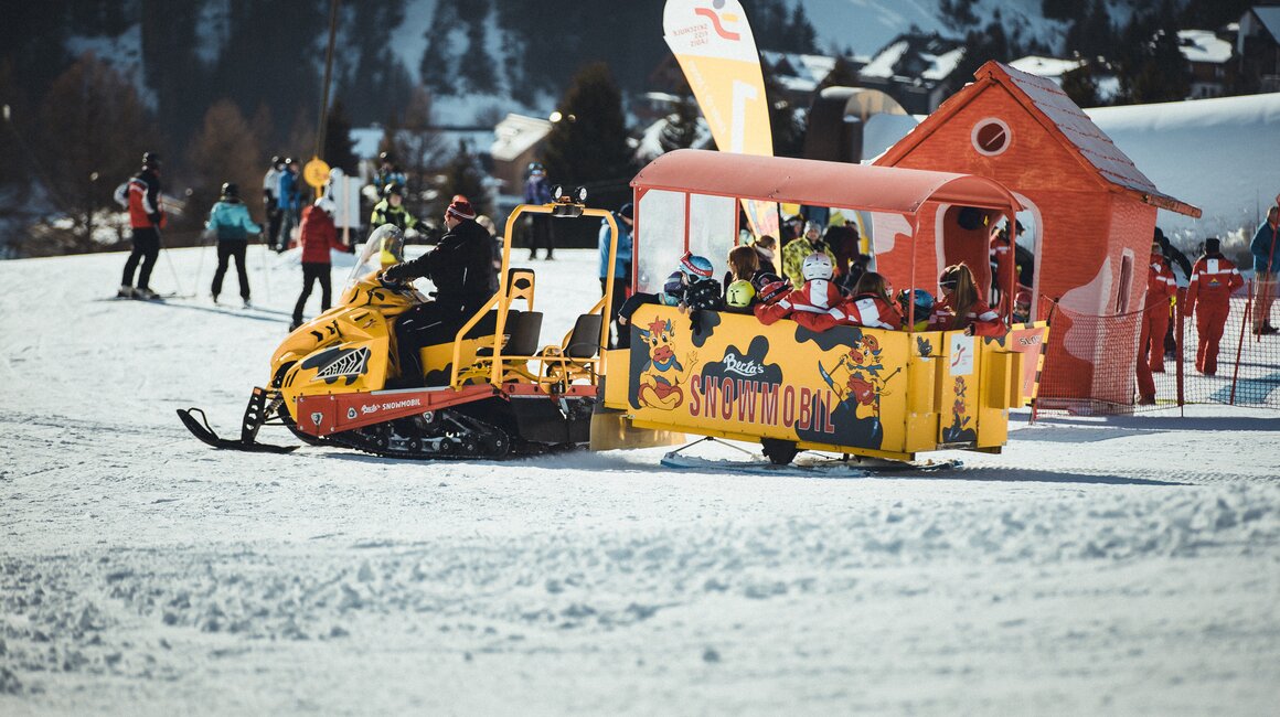 A snowmobile with passengers on a snowy slope.