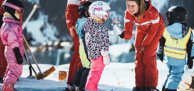 Ski instructor helping children ski in the mountains.