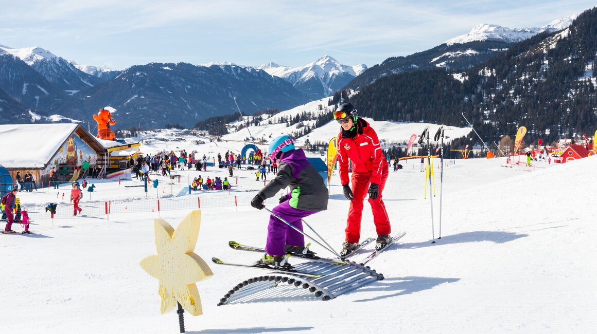 Ein Kind lernt Skifahren mit einem Lehrer bei schöner Winterlandschaft.