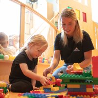 A caregiver and a child are playing together with LEGO blocks.