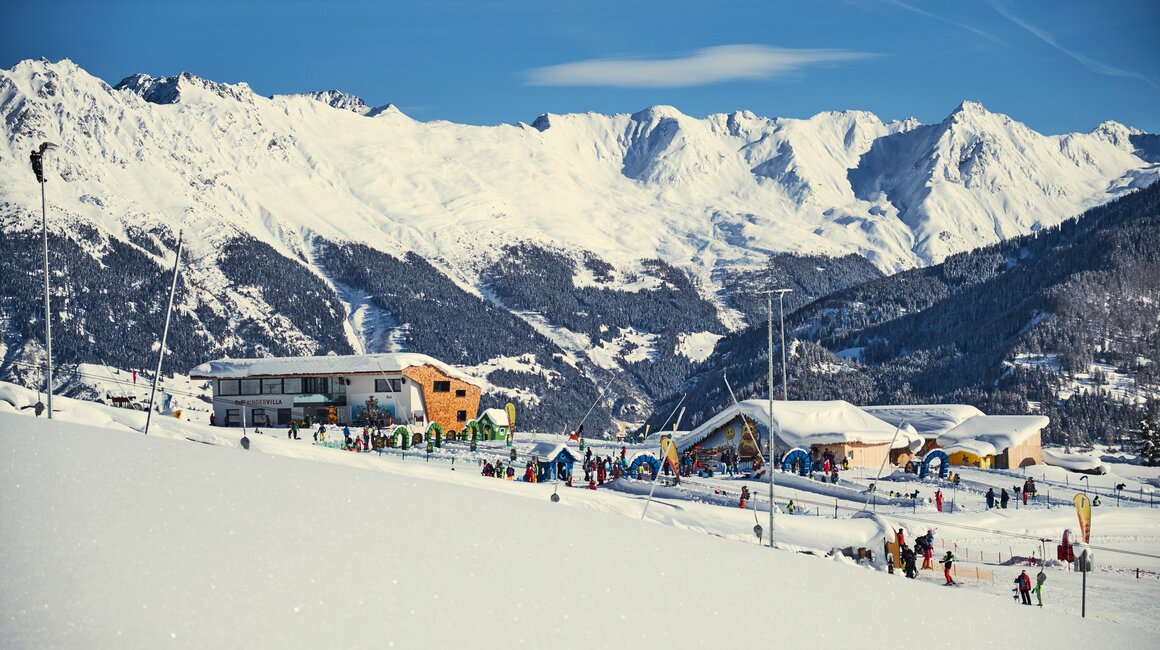 Ski resort featuring snow, buildings, and many holiday skiers.