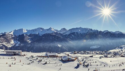 Snow-covered mountains and skiers under the sun.