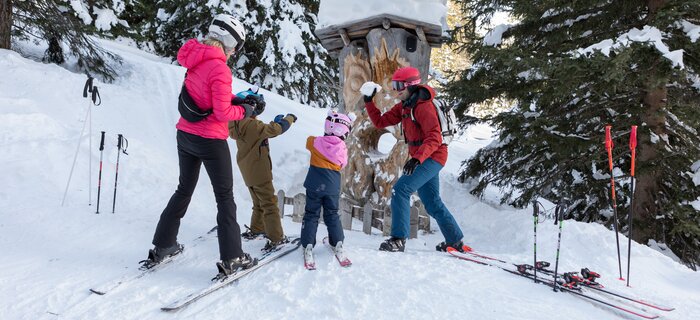 Familie genießt den Schnee beim Skifahren; Berglandschaft im Hintergrund.