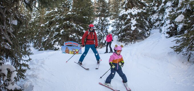 A family with a child skiing in a snowy landscape.