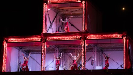Five dancers in red costumes under bright lights.