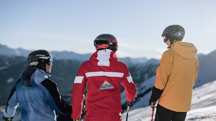 Three skiers looking at the mountains on a clear day.