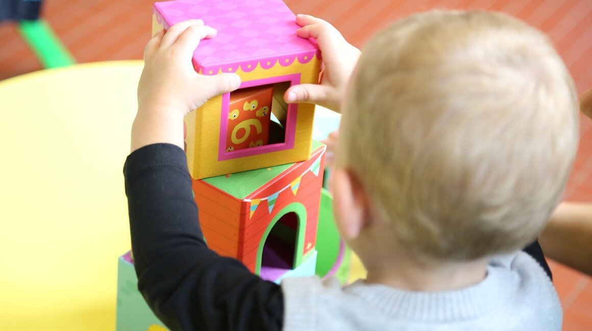 A child stacking colorful blocks on a tabletop.