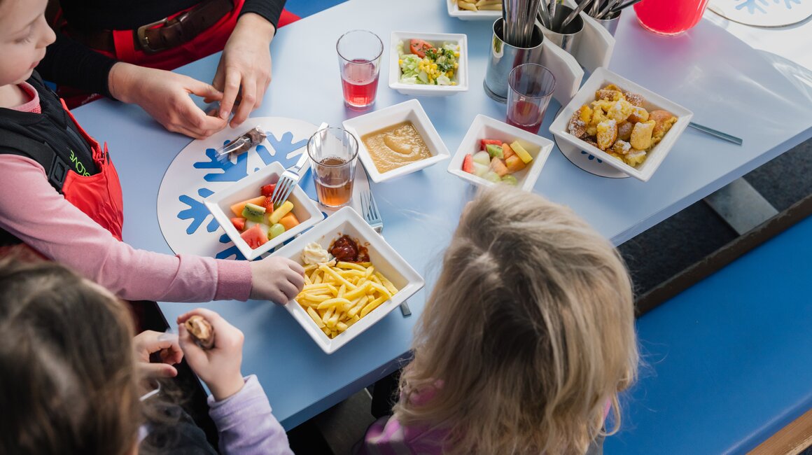 A group of children enjoying a meal together with adults in a cozy setting.