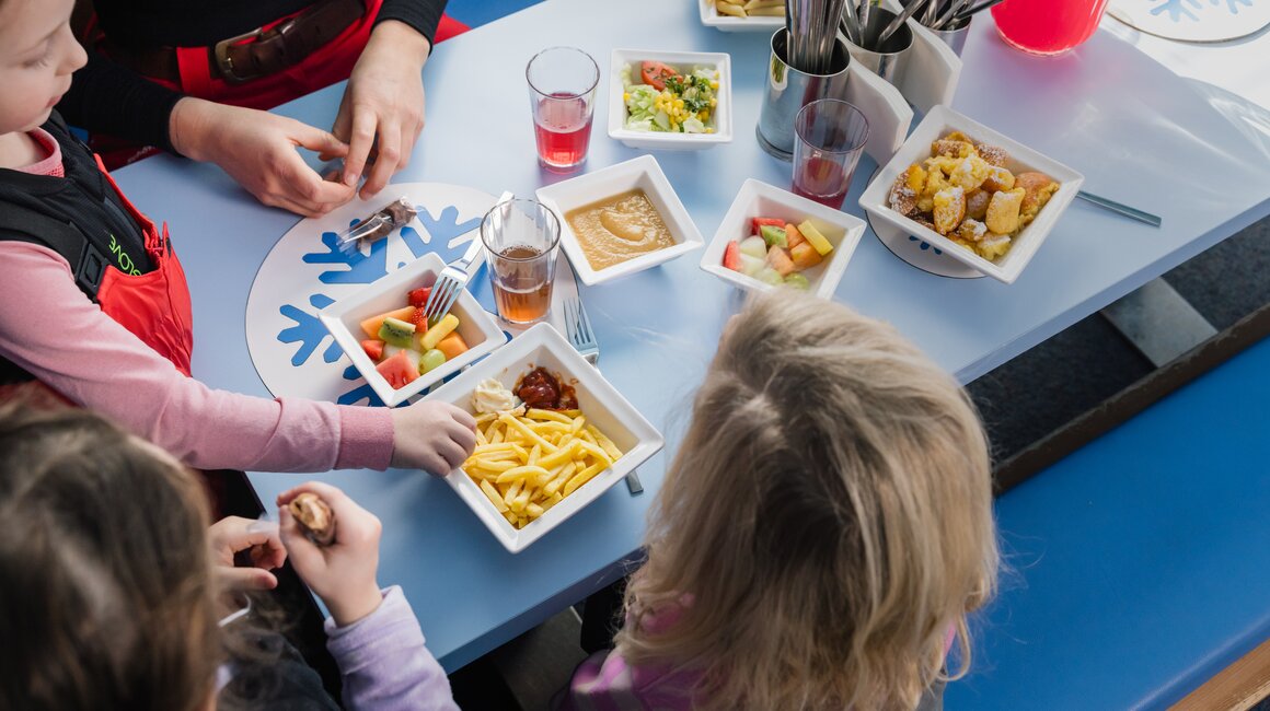 A group of children enjoying a meal together with adults in a cozy setting.