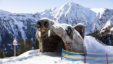 A snow-covered bear head entrance in a winter landscape.