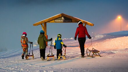 Family with sleds in the snow, ready to go.