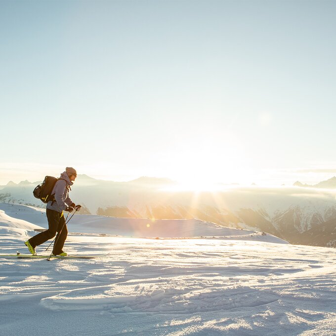 Ein Skifahrer wandert auf verschneiten Bergen bei Sonnenaufgang.