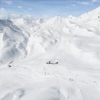 Weite schneebedeckte Berge mit einem Skigebiet im Bild.