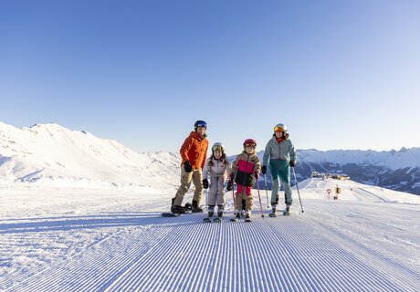 A family poses on a snowy slope while skiing.