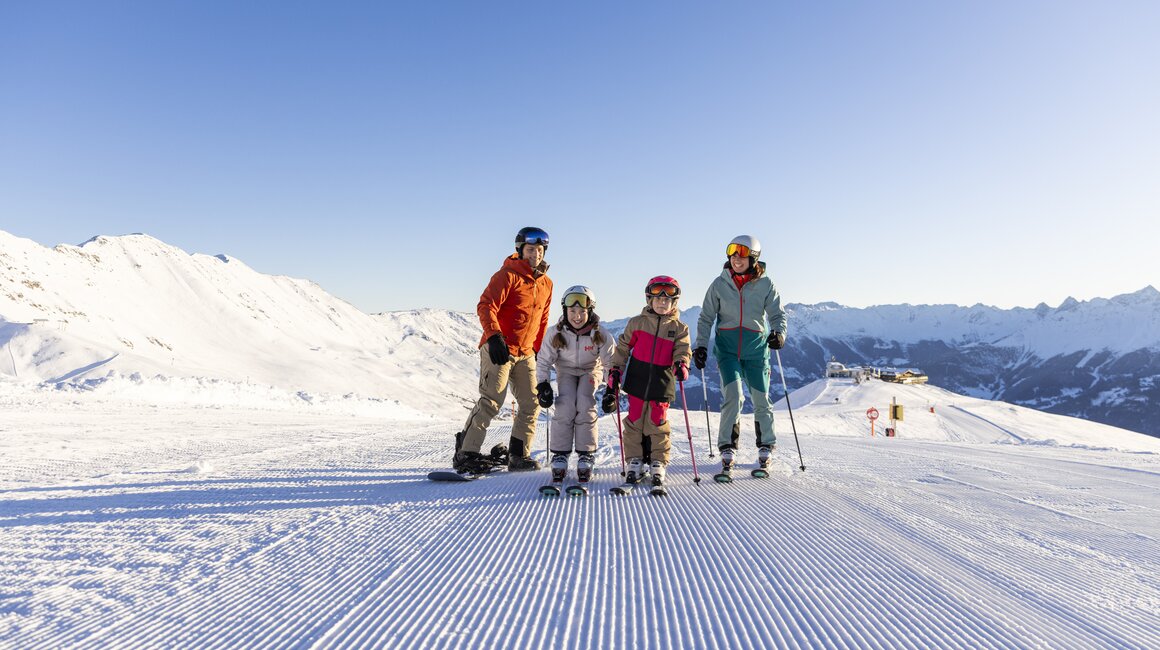 Een gezin poseert op een besneeuwde helling tijdens het skiën.