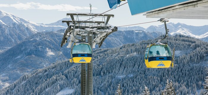 Colorful cable cars glide over snowy mountain peaks.