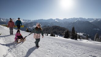 Eine Familie genießt den Schnee mit einem Schlitten.