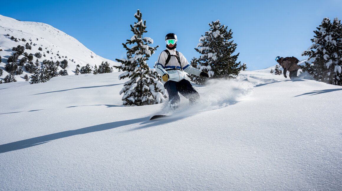 Ein Skifahrer gleitet durch frischen Schnee in den Bergen.