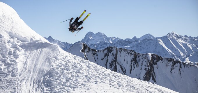 Ein Skifahrer vollführt einen Sprung in schneebedeckter Umgebung.