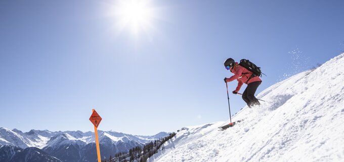 Eine Person fährt Ski in den Bergen an einem sonnigen Tag.