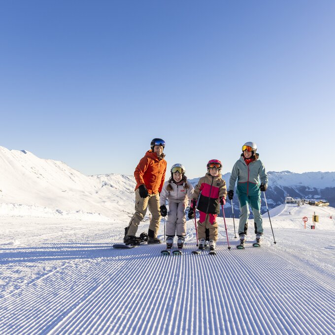 A family poses on a snowy slope while skiing.
