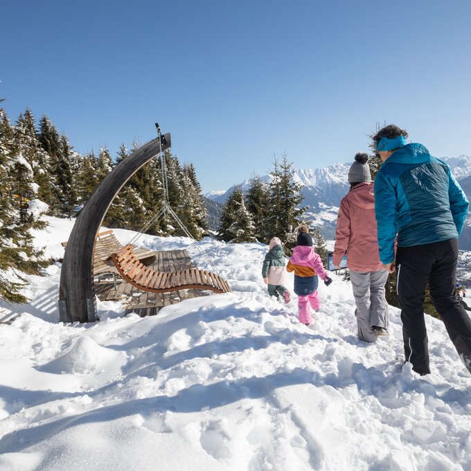 Een gezin wandelt door de sneeuw in de bergen en geniet van het uitzicht.