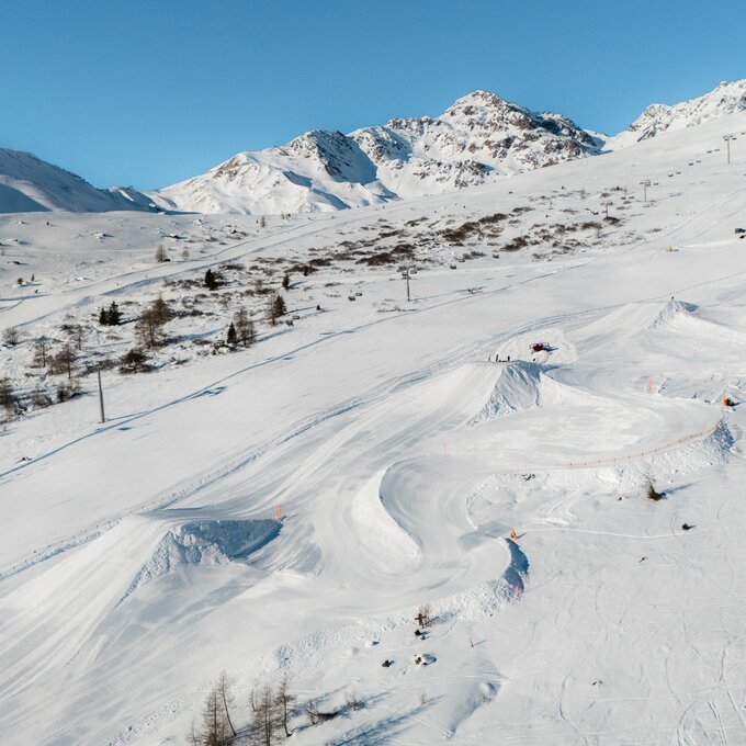 Ski trails with jumps in a snowy landscape and mountains.