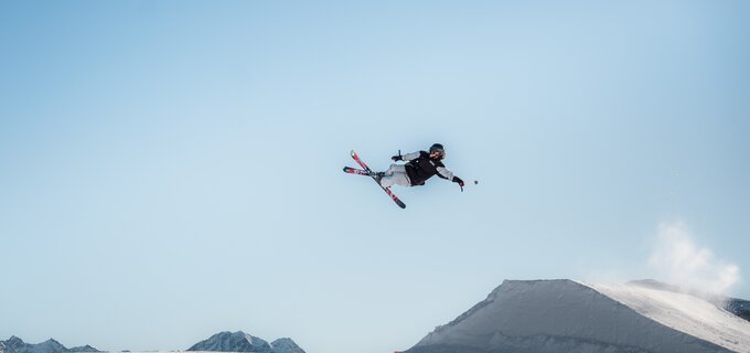 A skier jumps through the air over a snowy landscape.
