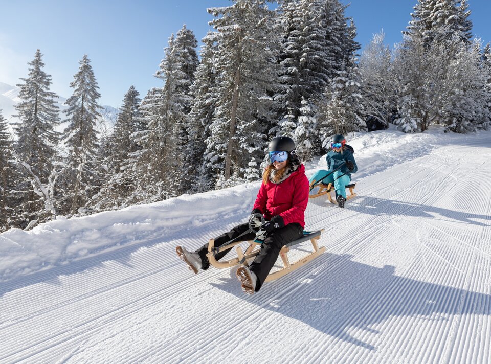 Zwei Frauen auf Schlitten genießen den verschneiten Wintertag.