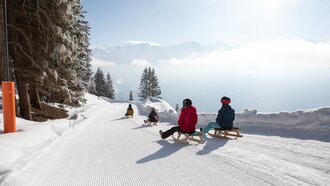 Familie genießt das Rodeln in den verschneiten Bergen.