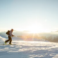 Ein Skifahrer wandert auf verschneiten Bergen bei Sonnenaufgang.