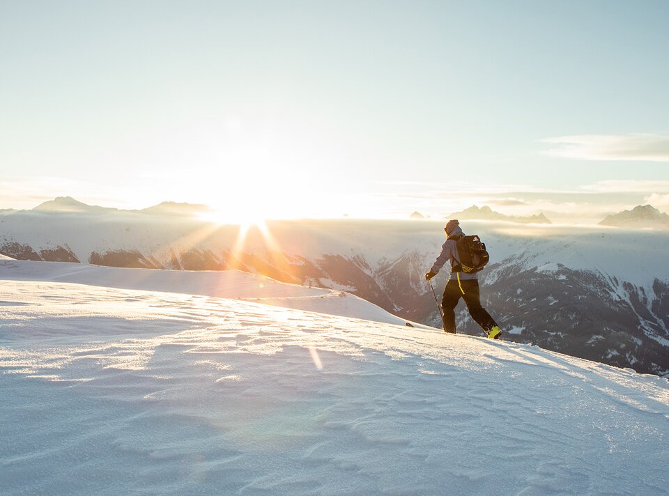 Een wandelaar beweegt zich door de sneeuw bij zonsopgang.