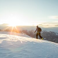 Ein Wanderer bewegt sich durch den Schnee bei Sonnenaufgang.