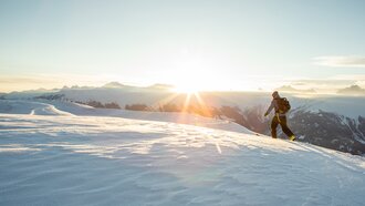 Ein Wanderer bewegt sich durch den Schnee bei Sonnenaufgang.