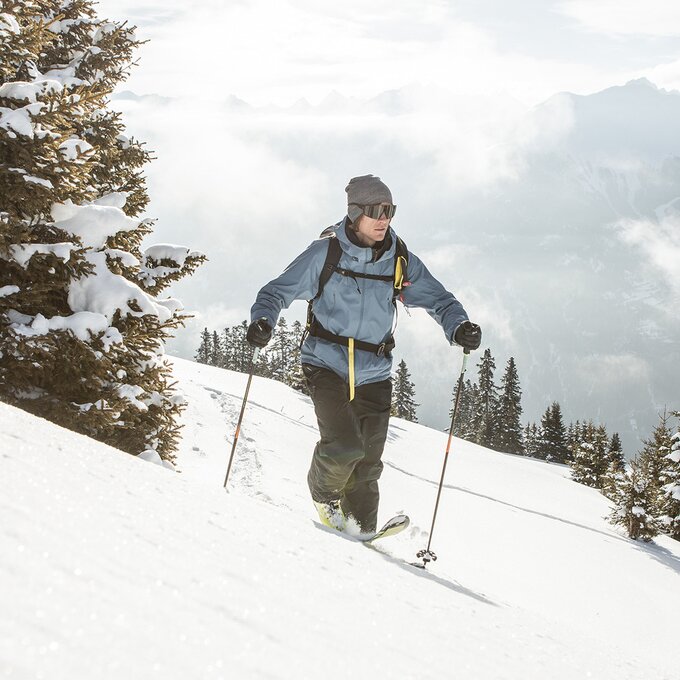 Een skiër glijdt door besneeuwde bergen onder een blauwe lucht.