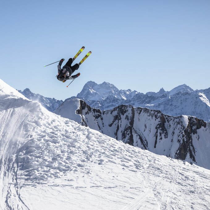 A skier performs a jump in a snowy landscape.